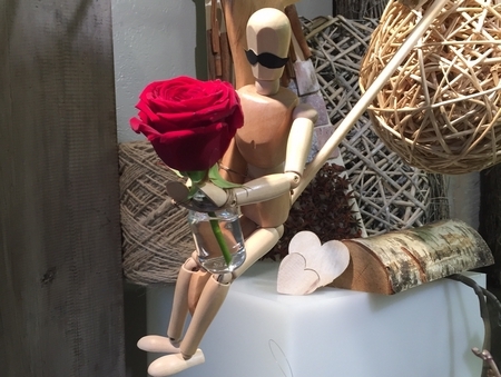 Wooden mannequin holding a red rose to evoke Valentine's Day