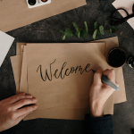 Une personne écrit le mot "Welcome" sur une feuille de papier