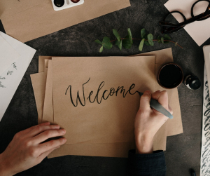 Une personne écrit le mot "Welcome" sur une feuille de papier