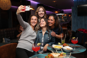 Plusieurs jeunes femmes faisant un selfie dans un bar