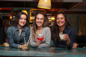 trois jeunes femmes qui boivent l'apéritif dans un bar