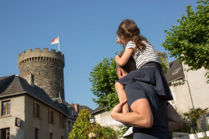 Un père porte sa fille sur ses épaules et ils regardent en direction de la tour César d'Allassac