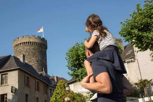 Een vader draagt zijn dochter op zijn schouders en ze kijken in de richting van de Caesar toren in Allassac.