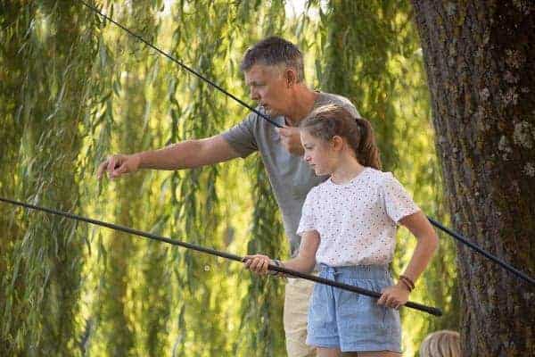 Un père et sa fille son en train de pêcher au bord du larc du Causse
