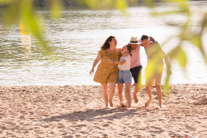 Une famille s'enlace et rit aux éclats sur la plage du lac du Causse