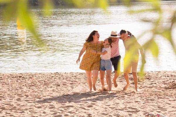 A family embraces and laughs their hearts out on the beach at Lac du Causse