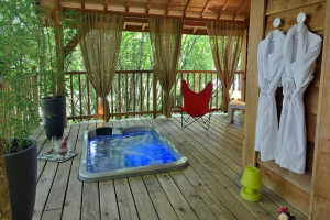 Vue sur un jacuzzi installé sur la terrasse d'une cabane en bois