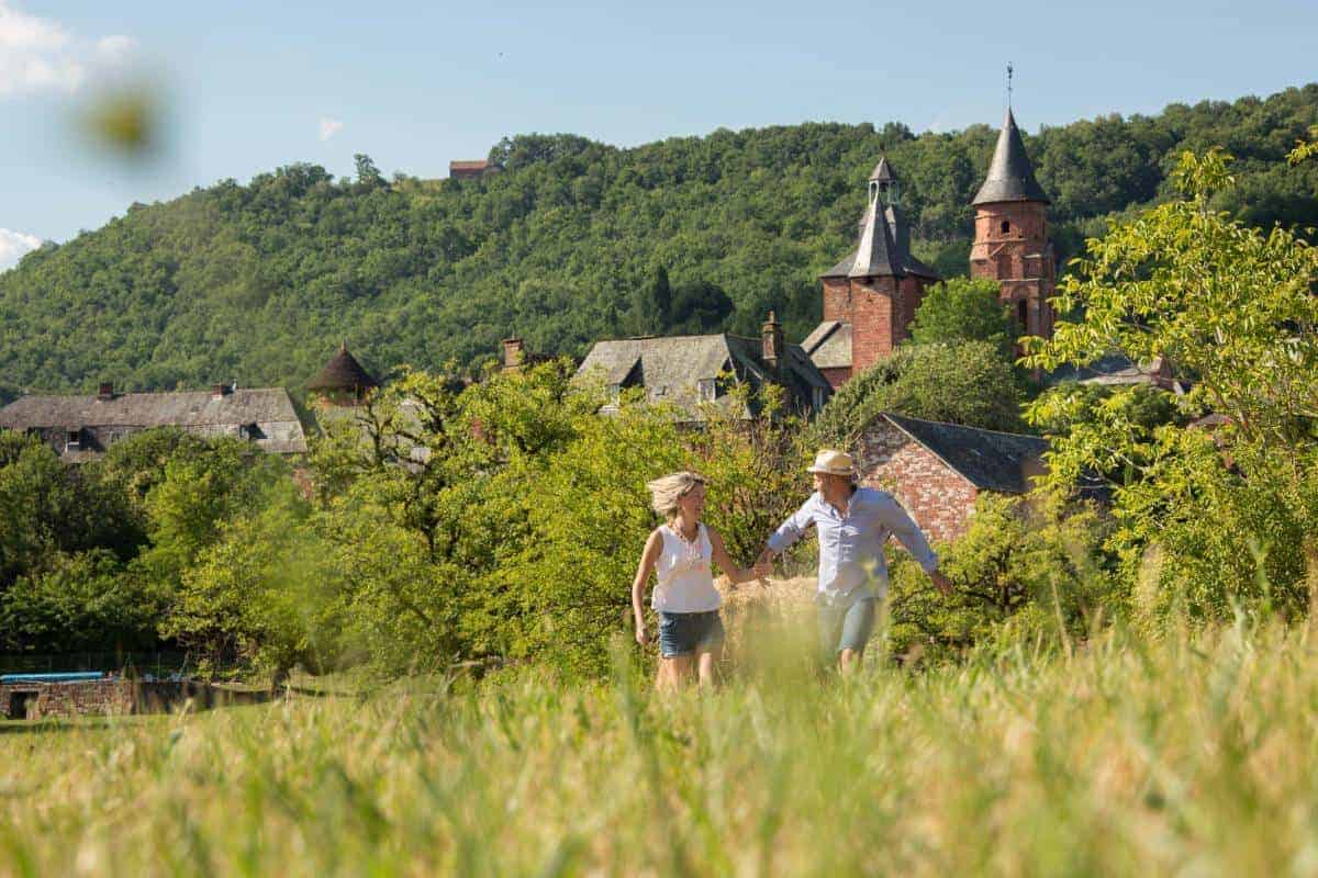 Deux personnes qui courent dans un champ de verdure avec le village en fond