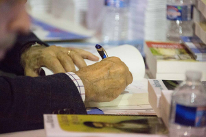 Vue sur la main d'un auteur en train de dédicacer un livre