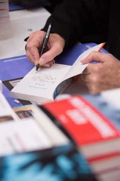 Vue sur la main d'un auteur en train de dédicacer un livre