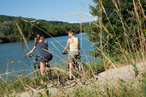 Deux femmes sont sur leurs VTT et devant le lac du Causse