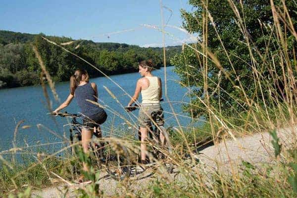 Deux femmes sont sur leurs VTT et devant le lac du Causse