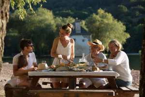 Une famille est en train de manger sur une table de pique-nique au lac du Causse