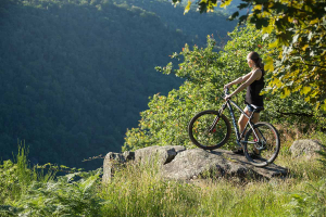 Une femme est sur un VTT sur un rocher dominant le barrage du Saillant