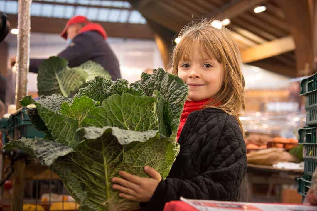 Niña con un enorme repollo en brazos