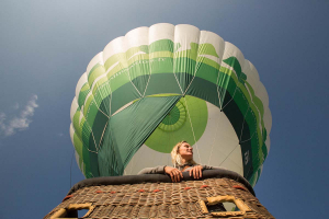 Vue en contre-plongée sur une jeune femme installée dans la nacelle d'une montgolfière