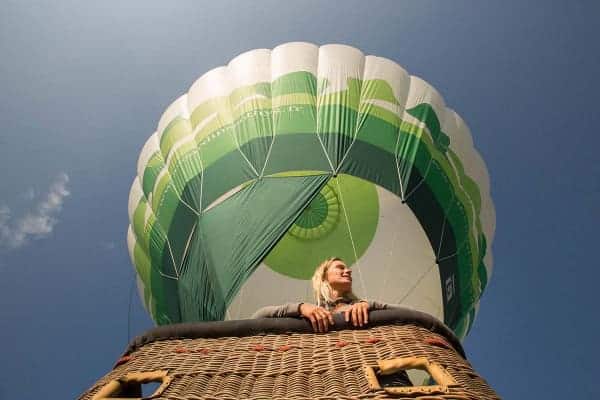 Onderaanzicht van een jonge vrouw in de mand van een heteluchtballon