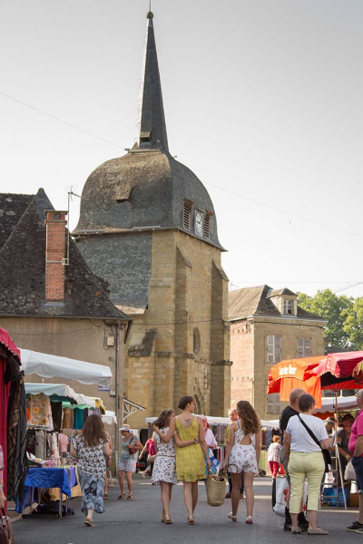 View of the bell tower of the Objat church with the market in front