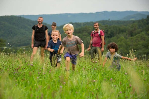 Une famille en train de marcher dans un pré avec un paysage vallonné à l'arrière-plan