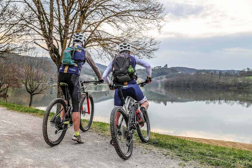 Vue de dos deux hommes qui font du VTT au lac du causse