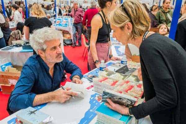 Un autor conversa con uno de sus lectores en su caseta de la Feria del Libro.