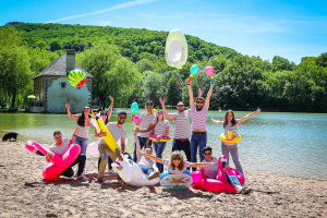 Photo de groupe de gaillards avec des bouées sur la plage du lac du Causse