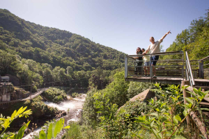 Une famille est sur une pacerelle au-dessus du barrage du Saillant durant une activité de pleine nature