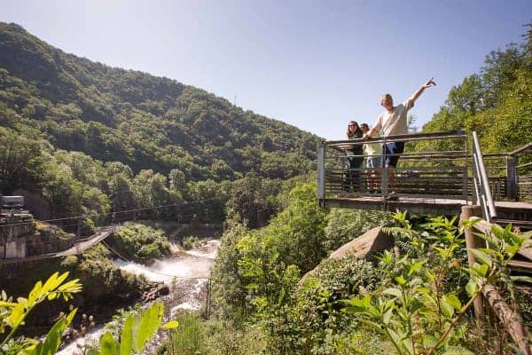 Une famille est sur une pacerelle au-dessus du barrage du Saillant durant une activité de pleine nature