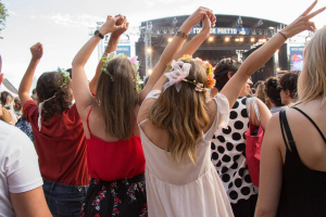 Groupe de filles avec des couronnes de fleur les bras en l'air de dos, tournés vers la scène