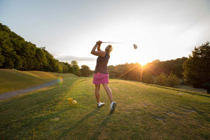 Une femme ajuste son swing avec un coucher de soleil à l'arrière-plan