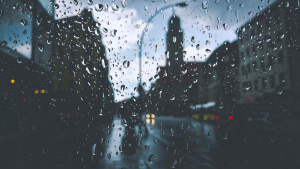 Une ville sous la pluie, vue derrière une vitre où des gouttes d'eau se sont déposées