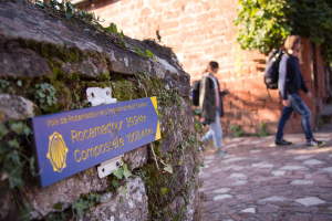 Vue sur un panneau indiquant le chemin de Compostelle avec un couple de marcheurs à l'arrière-plan