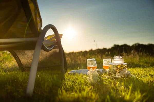 Un transat vu de derrière avec un plateau apéritif posé dans l'herbe