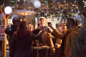 Persponnes trinquant devant les chalets du marché gourmand de Brive lors des animations de Noël