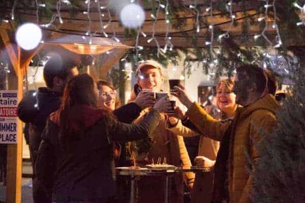 Persponnes trinquant devant les chalets du marché gourmand de Brive lors des animations de Noël