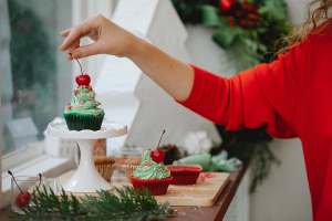 Une femme dépose une cerise sur un cupcake de Noël