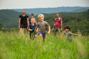 Des enfants courent dans un champ sous le regard de leurs parents