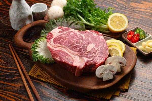 raw prime rib on a plank with condiments