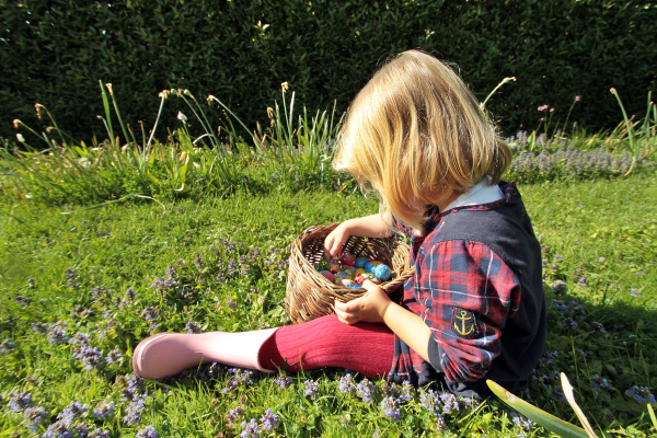 Petite fille avec son panier plein d'oeufs au chocolat après une chasse aux oeufs pour Pâques