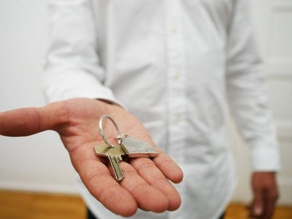 Eén persoon steekt een hand uit met een sleutel. Een sleutel van een vakantiewoning