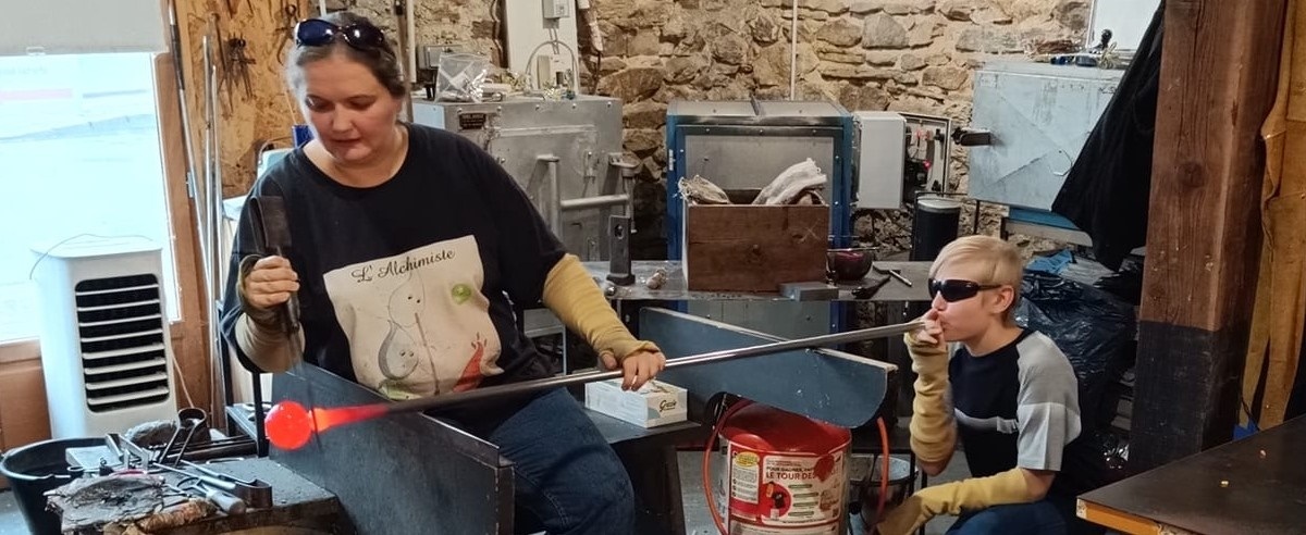 ©L'Alchimiste Un enfant réalisant une boule de Noël à l'Alchimiste, souffleur de verre à Uzerche.