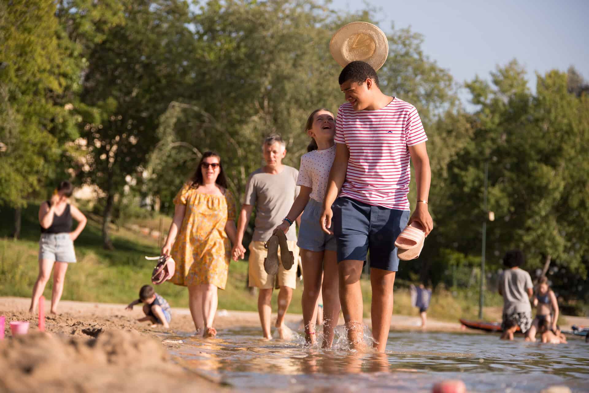 Famille faisant une balade les pieds dans l'eau au Lac du Causse