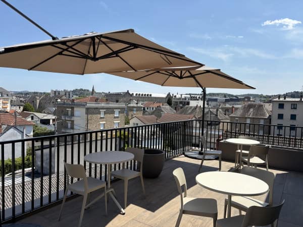 Terrasse en rooftop avec parasol, vue panoramique sur Brive, idéale pour se détendre ou prendre un repas en extérieur. Terrasse en rooftop avec parasol et vue sur la ville de Brive.