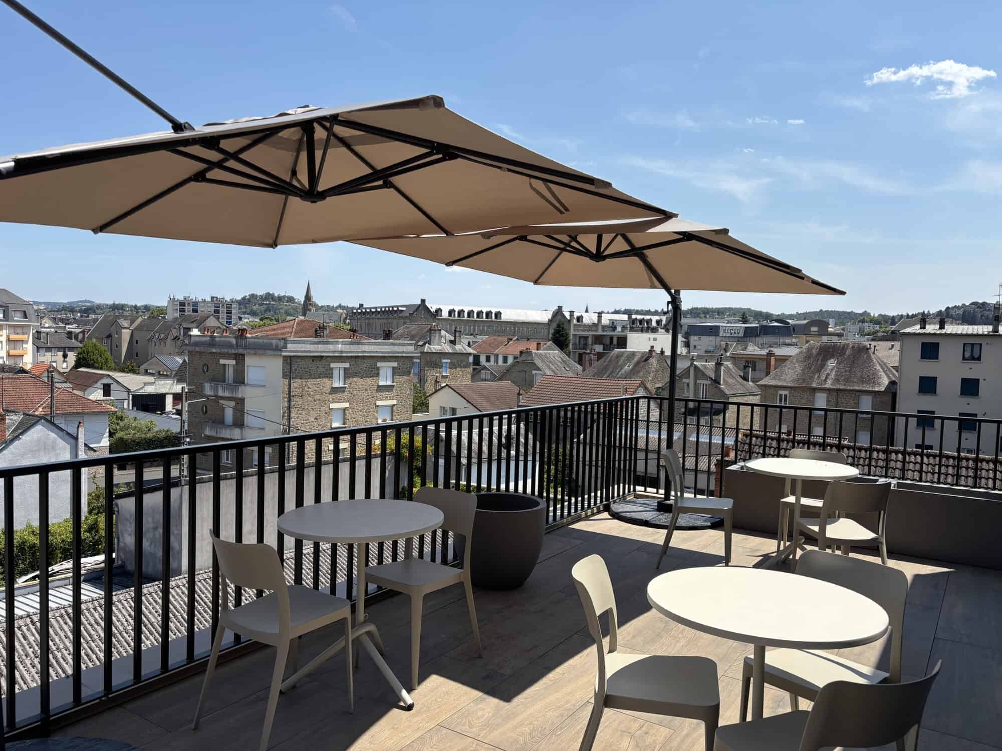 Terrasse en rooftop avec parasol et vue sur la ville de Brive.