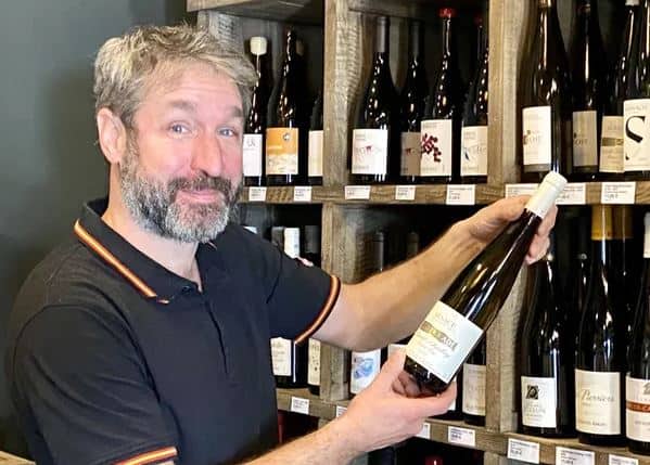 Olivier Leydier, caviste près de Brive, debout à côté des bouteilles de vin