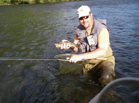 un pecheur tenant un poisson dans une riviere